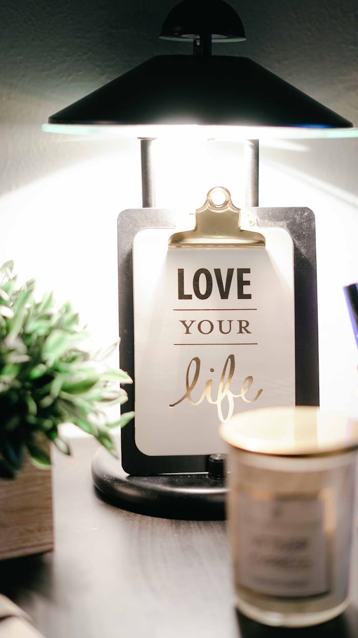 A warmly lit desk setup featuring a lamp, inspirational clipboard, and decor for a cozy ambiance.